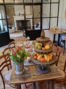 - une table en bois avec des assiettes de fruits et de fleurs dans l'établissement Mas Armelin, à Tarascon