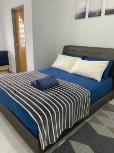 a bed with a blue and white blanket and pillows at Al-Amin Homestay, Jasin, Melaka in Jasin