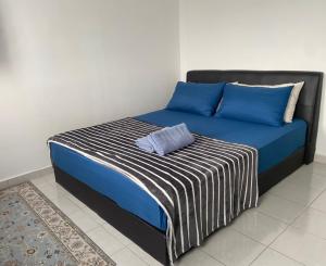 a bed with blue and white sheets and blue pillows at Al-Amin Homestay, Jasin, Melaka in Jasin