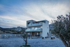 una casa bianca con degli alberi di fronte di Aquamarine Luxury Suites a Archangelos