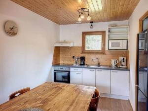 a kitchen with a wooden table and a wooden ceiling at Le chalet des Broches - jacuzzi in Xonrupt-Longemer