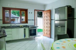 eine Küche mit Kühlschrank, Spüle und Tür in der Unterkunft NOVO Maravilhosa casa de campo em Mairipora SP in Mairiporã