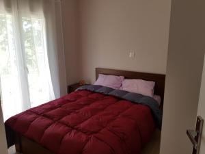 a bed with a red comforter in a bedroom at Dimas House in Kanallaki