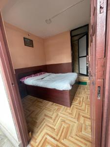 ein kleines Schlafzimmer mit einem Bett und einem Holzboden in der Unterkunft Nirvaan Guest House (Hotel Bibidh) in Kathmandu