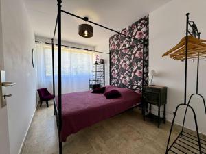een slaapkamer met een hemelbed met een paarse sprei bij Appartement avec sur la mer ! in Sagone