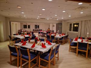 um salão de banquetes com mesas e cadeiras com guardanapos vermelhos em Norsjø Hotell em Akkerhaugen