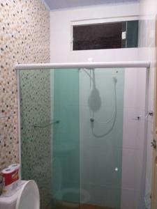 La salle de bains est pourvue d'une douche en verre et de toilettes. dans l'établissement Casa confortável e bem localizada, à Macapá