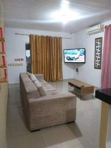 uma sala de estar com um sofá e uma televisão de ecrã plano em Casa confortável e bem localizada em Macapá