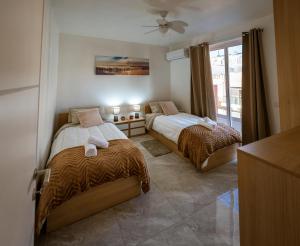 Un dormitorio con dos camas y una ventana. en Malta Serenity Home, en Marsaskala