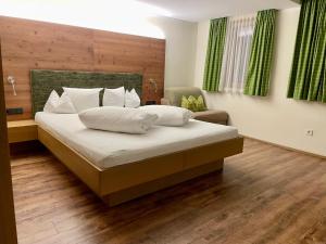a bedroom with a large bed and a chair at Aktivhotel Tuxerhof in Zell am Ziller