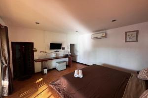 een slaapkamer met een bed en een bureau met een televisie bij Ozone Resort & Pool Villa in Phatthalung