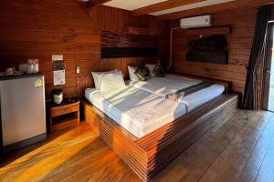 uma cama grande num quarto com paredes de madeira em Ozone Resort & Pool Villa em Phatthalung