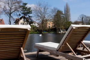 zwei Gartenstühle auf einem Steg neben einem See in der Unterkunft Villa Privée avec Piscine et Lac in Saint-Gratien