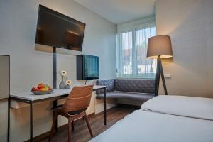 a hotel room with a bed and a desk with a television at Ringhotel Gasthof Hasen in Herrenberg