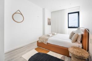 ein weißes Schlafzimmer mit einem Bett und einem Spiegel in der Unterkunft GuestReady - A lovely vacation in Matosinhos in Matosinhos