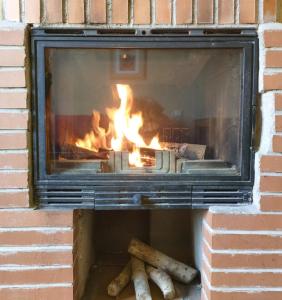 a brick fireplace with a fire in it at Alojamientos El Castillo in El Berrueco
