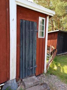 a woodenshed with a door on the side of a house at Hemma fran Hemma - Stuga in Kvillsfors