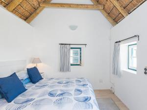 1 dormitorio blanco con 1 cama grande con almohadas azules en Zandtorini Seaside Cottage, en Struisbaai