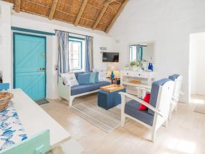 sala de estar con sofá azul y mesa en Zandtorini Seaside Cottage, en Struisbaai