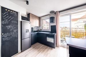 eine Küche mit einem schwarzen Kühlschrank und einem großen Fenster in der Unterkunft Appartement Proche Disney Paris Vidéo-Projecteur in Bussy-Saint-Georges