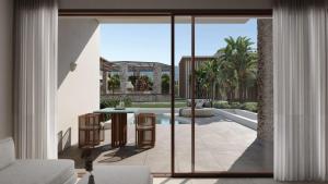 una sala de estar abierta con puertas correderas de cristal y un patio. en PEARL ISLAND CHIOS HOTEL & SPA, en Chios