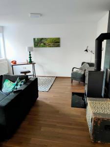 ein Wohnzimmer mit einem schwarzen Sofa und einem Kamin in der Unterkunft Ferienwohnung Waldeule in Bad Kissingen