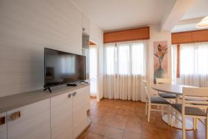 uma sala de estar com televisão e uma mesa com cadeiras em Residence Piccolo em Milano Marittima
