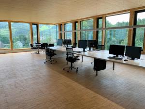 Duży pokój z biurkiem, krzesłami i oknami w obiekcie Ferienwohnung iq-Sports w mieście Bludenz