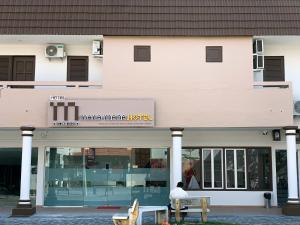 a man sitting on a bench in front of a building at Mana Mana Hotel • Melaka • in Melaka