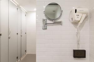 a white bathroom with a mirror and a shower at Double B Hostel in Bangkok
