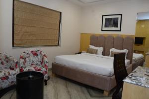 ein Hotelzimmer mit einem großen Bett und einem Stuhl in der Unterkunft CRYTSAL RESIDENCY in Ranchi