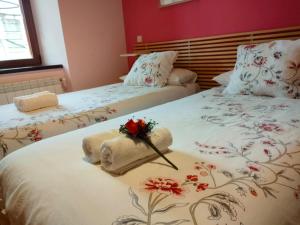 two beds with towels and a bouquet of flowers on them at Alojamiento Antigua Casa de Telefonos in El Berrueco