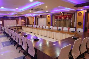 ein großer Konferenzraum mit einem langen Tisch und weißen Stühlen in der Unterkunft Hotel Raj in Puri