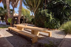 un banco de madera sentado en un parque con palmeras en Spacious Villa- Private Pool/ 8BR/@Playa Den Bossa, en Sant Josep de sa Talaia