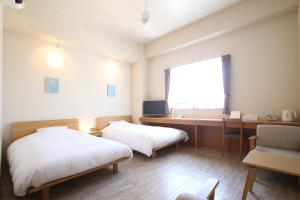 een kamer met 2 bedden en een bureau met een computer bij Ishigakijima Hotel Cucule in Ishigaki Island