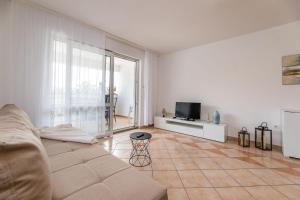 a white living room with a couch and a television at Angie in Baška