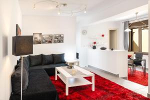 een woonkamer met een zwarte bank en een rood tapijt bij Garden Apartments in Rózia