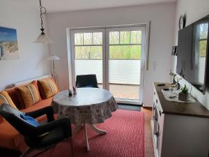 ein Wohnzimmer mit einem Tisch und einem Sofa sowie eine Küche in der Unterkunft Haus am Bürgerpark Hage EG in Hage