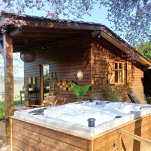 a hot tub in front of a log cabin at Les nids de Bonnan in Milhars