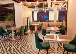 a dining room with tables and green chairs at Hotel Baga Bliss By Celestiial Hospitality, Baga North Goa in Goa
