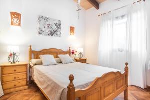 a bedroom with a wooden bed and a window at Can Juanito in Cala Llombards