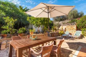 a wooden table with an umbrella on a patio at Can Juanito in Cala Llombards