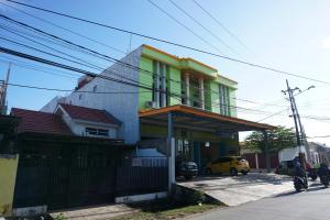 a building with a green and yellow house at OYO 93877 Atifah Homes in Sungguminasa