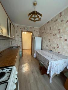 eine Küche mit einem Tisch und einem Kühlschrank in der Unterkunft Маринад in Petropawlowsk
