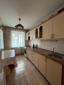 una cocina con armarios blancos y fregadero en Маринад, en Petropavlovsk