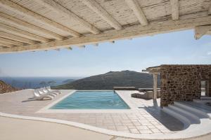 een zwembad met stoelen en een huis bij Mykonian Icon Villa in Mykonos-stad +70 foto's