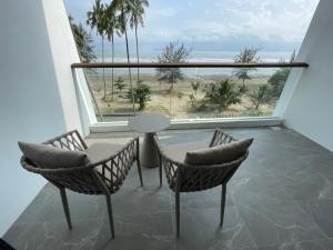 een balkon met een tafel en stoelen en uitzicht op het strand bij Freedom Flamingos-RoxyBeachApt in Sematan