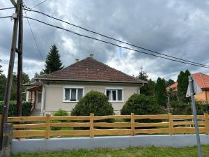 uma casa com uma cerca de madeira em frente em Örömvölgy Vendégház em Bózsva