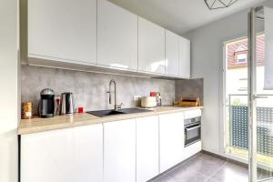 een keuken met witte kasten en een wastafel bij C4 Les Jardins d'Orsonville in Chessy