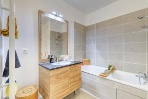 een badkamer met een bad, een wastafel en een bad tubermottermott bij C4 Les Jardins d'Orsonville in Chessy